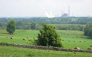 image, Shakertown field with stone wall and rolled hay; coal powerplant in background.