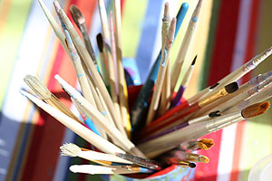 Paintbrushes against a colorful blanket table top at Ben's Bells studio.