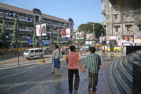 Couple holding hands outside Mumbai movie theater.