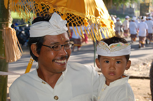 Balinese father and son with rice on foreheads.