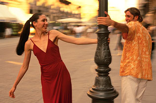 Couple swinging around a light post next to a plaza.