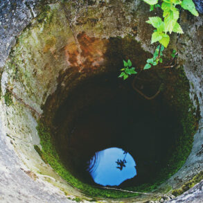 Old, mossy well with water visible at bottom