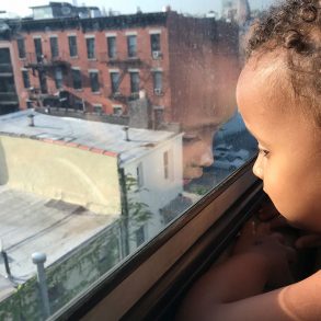 Child looking out window in Brooklyn