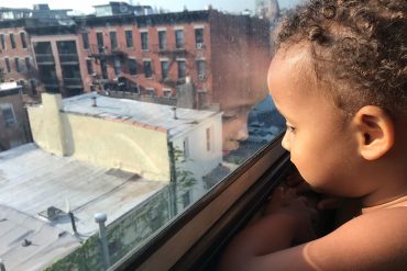 Child looking out window in Brooklyn