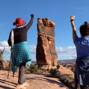 Women in desert raising fists