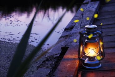 Hurricane lamp at twilight next to river