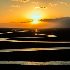 Sunset over winding river on prairie