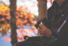 Woman holding binoculars with autumn lake background