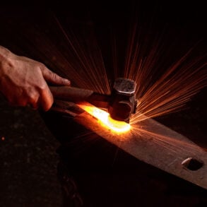Hand, hammer, anvil, and sparks