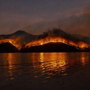 Wildfire on hills reflected in water