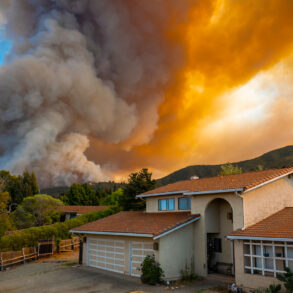 Suburban house with wildfire on horizon