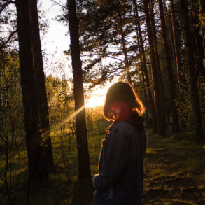 Silhouette of woman in woods at sunrise