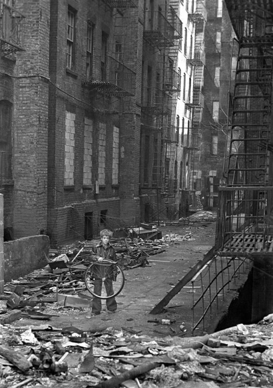 A boy plays near abandoned buildings