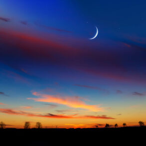 Crescent moon at dusk with rural silhouette