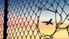 Airplane seen through hole in chain link fence
