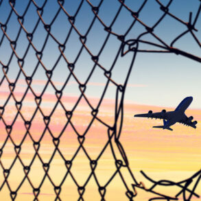 Airplane seen through hole in chain link fence