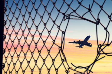 Airplane seen through hole in chain link fence