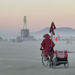 Monk on bicycle at Burning Man at twilight
