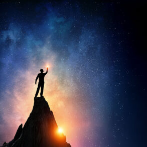 Silhouette of man on peak with stars