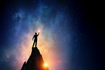 Silhouette of man on peak with stars