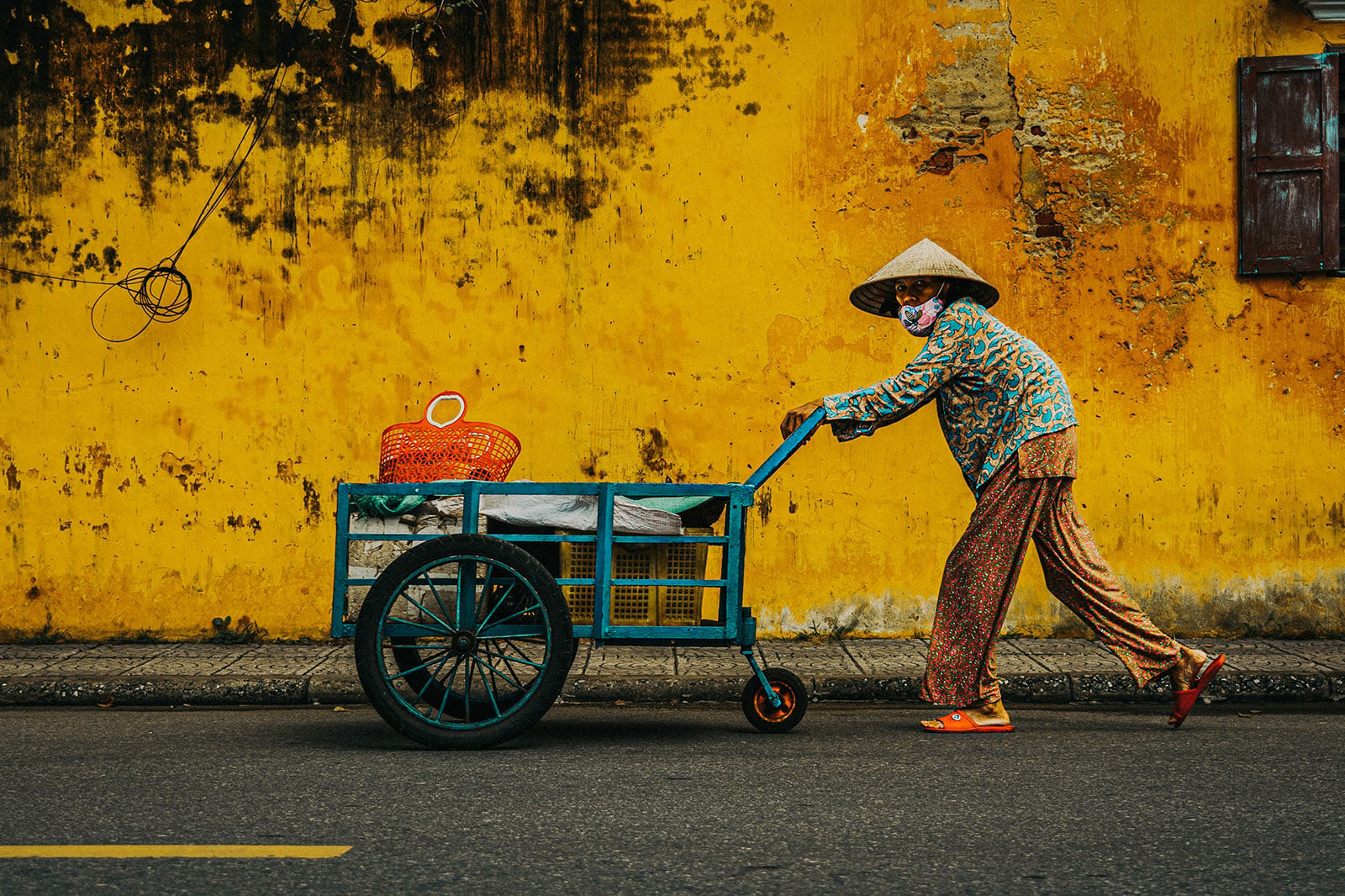 Woman pushing cargo through old town of Hoi An