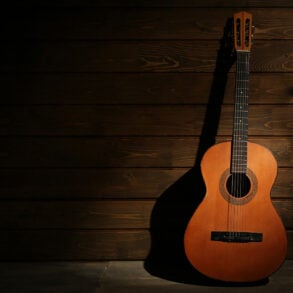 Warm light on acoustic guitar against wooden wall