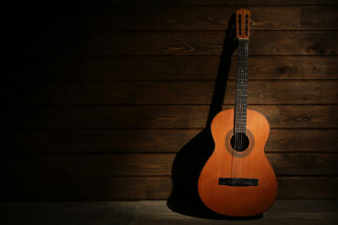 Warm light on acoustic guitar against wooden wall