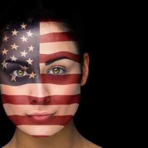 Female face painted with U.S. flag on black background
