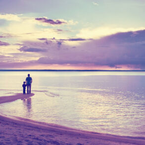 Silhouette of father and son on beach in soft light