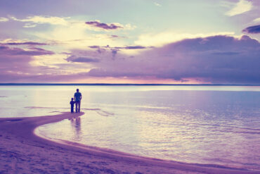Silhouette of father and son on beach in soft light