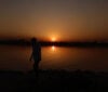 Silhouette of man at sunset next to water
