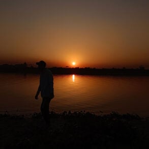 Silhouette of man at sunset next to water