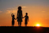 Silhouette of mother with children at sunset