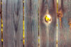 Backlit hole in wooden fence