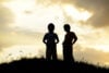 Silhouette of two boys on a hill