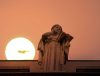 Statue of woman reading, with sun in background