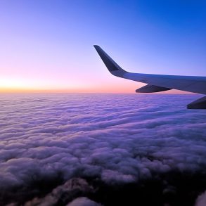 Plane wing above clouds at dusk