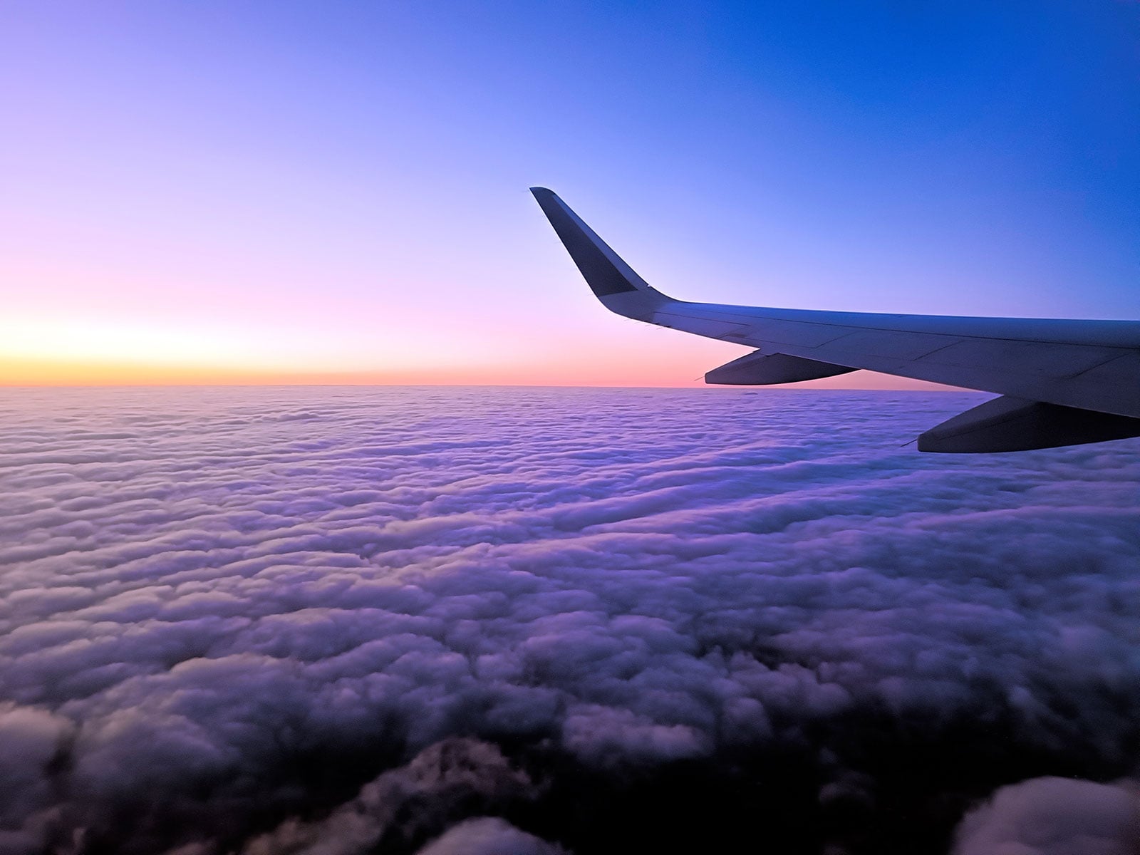 Plane wing above clouds at dusk