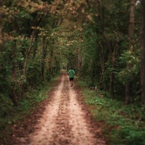 Male running on dirt road in woods