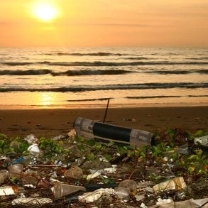 Trash on beach with joggers at sunset