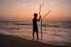 Silhouette of boy with stick on beach of Indian Ocean