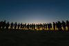 Line of people silhouetted against rising sun