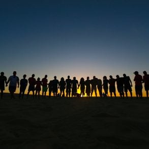 Line of people silhouetted against rising sun