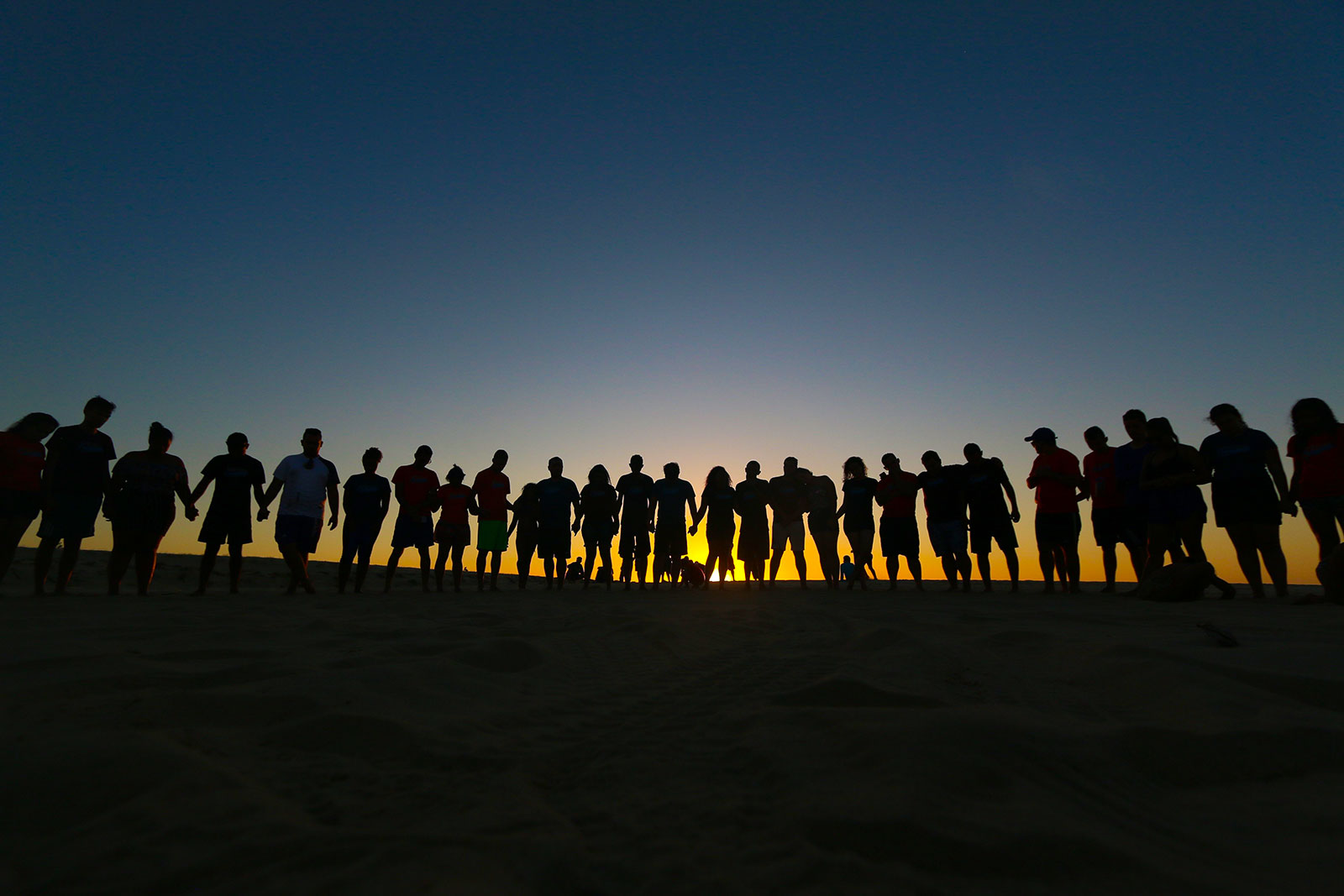 Line of people silhouetted against rising sun