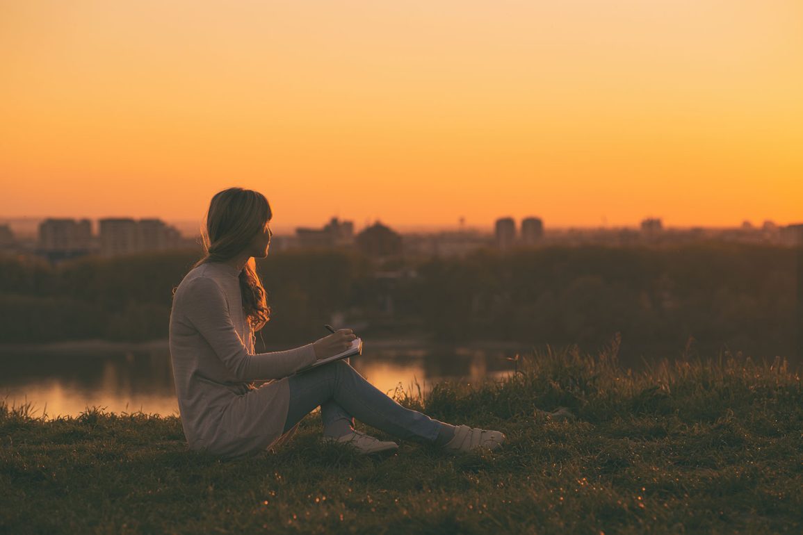 Young woman writing at sunset