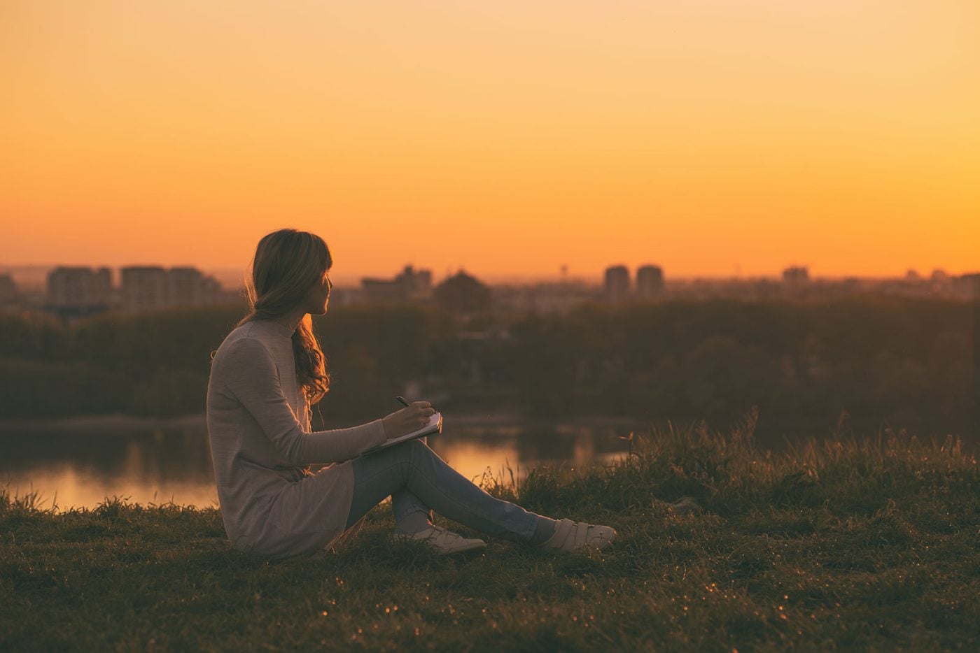 Young woman writing at sunset