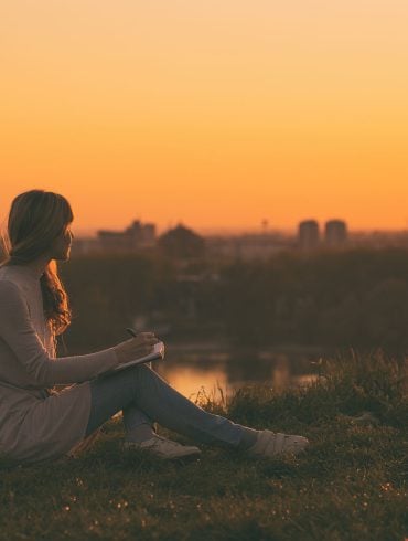 Young woman writing at sunset