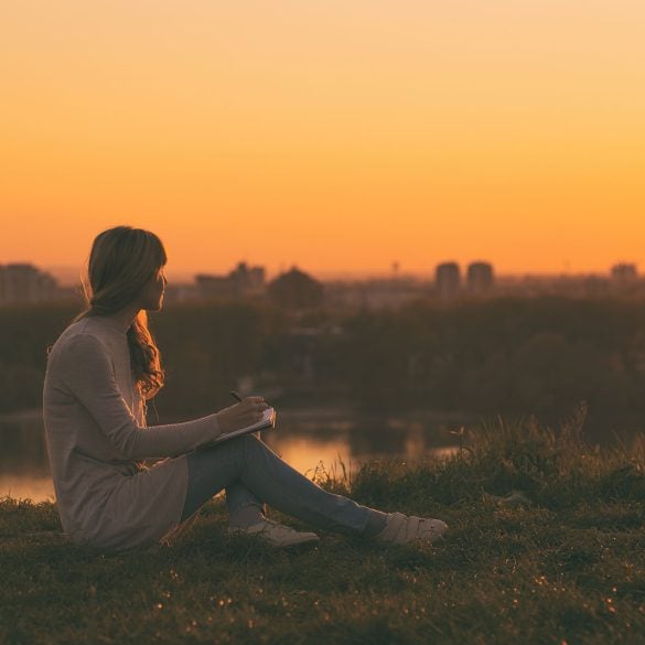 Young woman writing at sunset