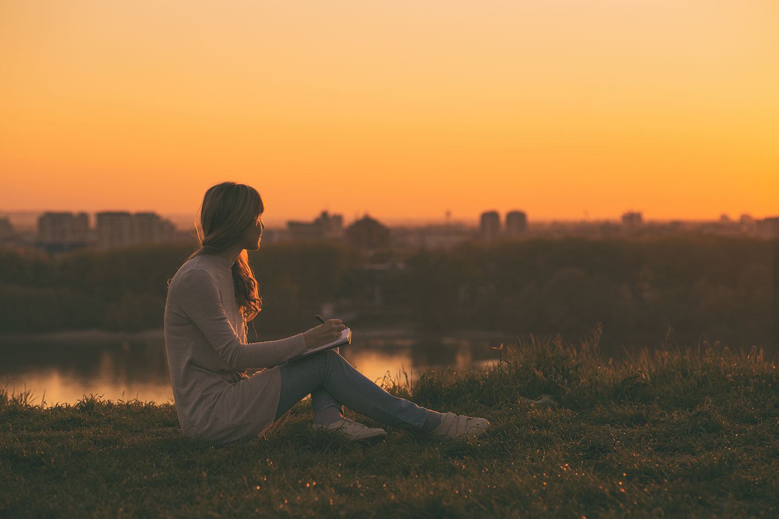 Young woman writing at sunset