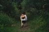 young girl with a backpack walking away through a forest